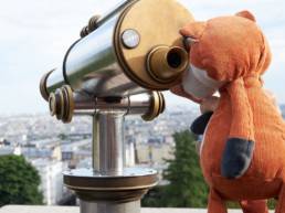 Mascotte de Foxtrail Paris qui regarde a travers un telescope